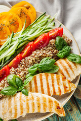 quinoa salad with grilled chicken and vegetables on wooden rustic background