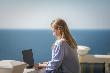 Beautiful girl freelancer with a laptop in front of the sea