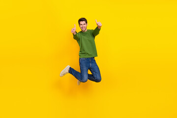 Photo of impressed sweet guy dressed green pullover jumping high showing thumbs up isolated yellow color background