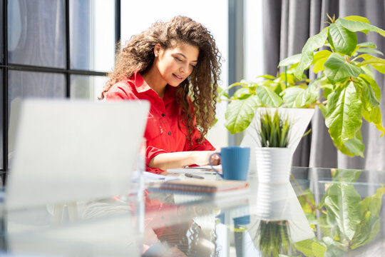 Attractive Cheerful Business Woman In Red Shirt Working On Laptop At Modern Office.