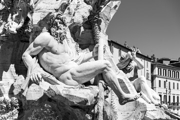 Black and white photo of statue of naked Neptune carved in a marble fountain in Rome