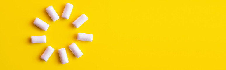 Top view of round shape from white chewing gums on yellow background, banner.