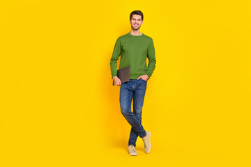 Fototapeta na wymiar Photo of funny attractive guy wear green sweater holding modern gadget empty space isolated yellow color background