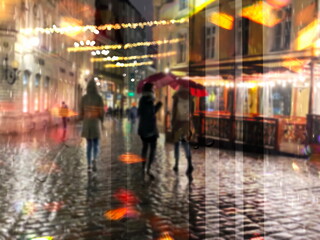 Obraz na płótnie Canvas rainy city night light street reflection people with umbrellas buildings blurred light red yellow bokeh vew from window urban Tallinn old town medieval holiday lifestyle