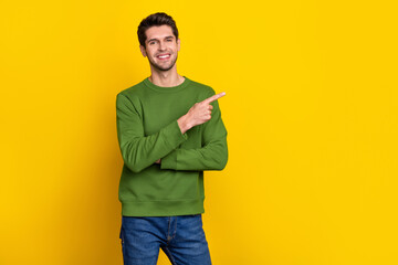 Photo of pretty attractive guy dressed green pullover pointing finger empty space isolated yellow...