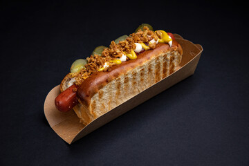 Hot dogs in paper plates with sausages and sauce 
