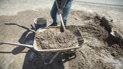 Worker prepare concrete with shovel at construction site.