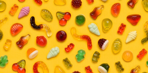 Seamless pattern of assorted jelly gum fruit candy on yellow background top view flat lay