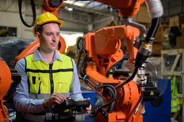 A male worker is controlling a welding robot. by using forcing welding with a control screen which is used for precision welding control. Fast and highly secure