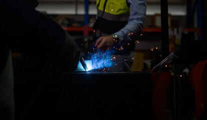 Welder working welding metal with Engineer to closely control the work in order to obtain the...
