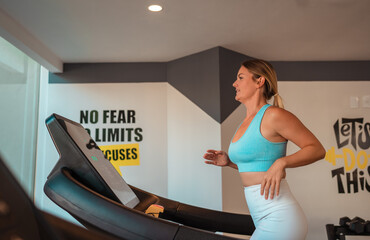 Fototapeta na wymiar blonde girl using a treadmill in the gym