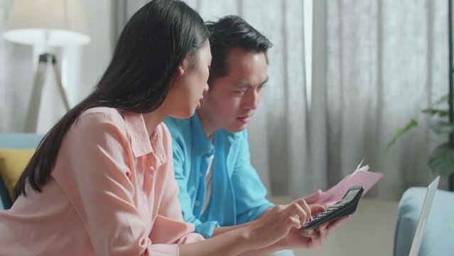 Close Up Of Asian Couple With A Laptop Being Sad After Helping Each Other Calculating Money By Calculator
