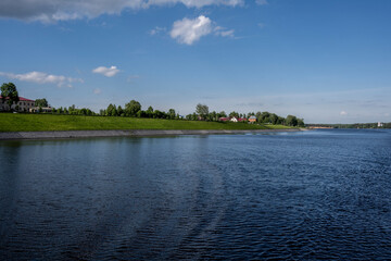 an old white-stone monastery on the banks of the river on a summer day