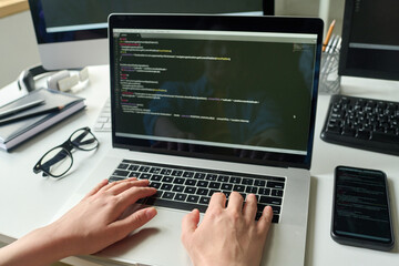 Close-up of female programmer typing on laptop new code of program at office desk