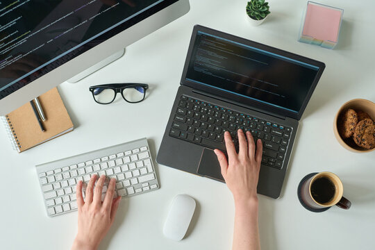 High angle view of young programmer writing code on laptop and using computer keyboard at table - Powered by Adobe