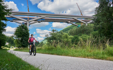 woman on electric mountain bike below the construction site for the new railway trail from...