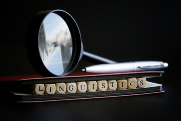 Word linguistics next to a fountain pen, notepad and magnifying glass. Сoncept of studying the...