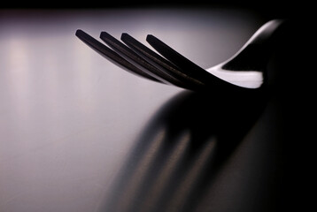 silhouette of a metal fork on dark background