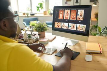 Photo editor working on desktop computer at office desk retouching photo with image editing software