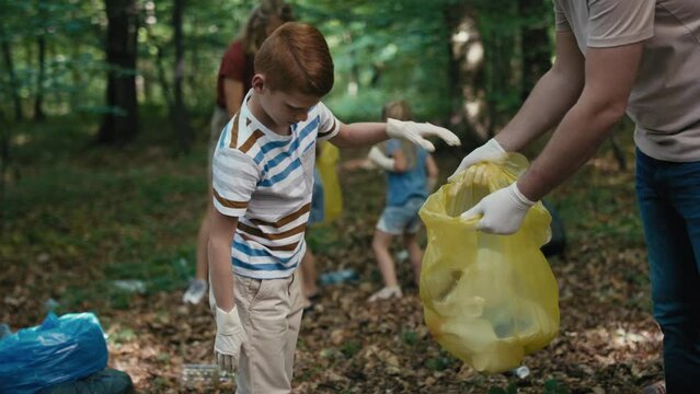 Caucasian boy cleaning forest from trashes with family. Shot with RED helium camera in 4K. 