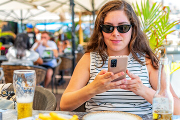 Happy caucasian woman using smart phone sitting at restaurant.