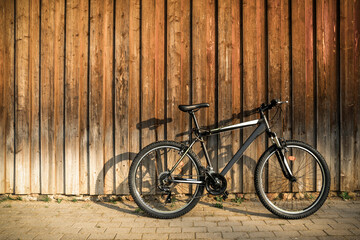 Fototapeta na wymiar Modern sport mountain bike leaning against brown wooden wall