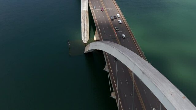 Aerial tilt up shot showing traffic on JK Bridge (Portuguese: Ponte JK ), a steel and concrete arch bridge across Lake Paranoa in Brasilia, Federal District, capital of Brazil.	
