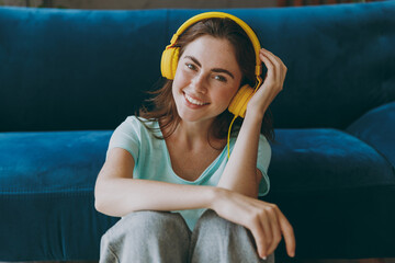 Young fun smiling satisfied fun woman she in casual clothes mint t-shirt headphones listen to music...