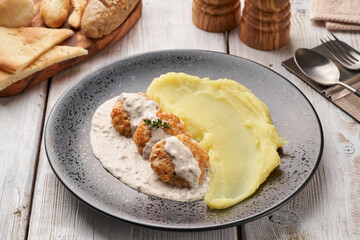 Fresh homemade creamy mashed potato or potato puree with chicken meatballs in beshamel sauce.