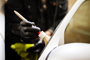 Man in uniform and respirator, worker of car wash center, cleaning car interior cleaning brush . Car detailing concept.