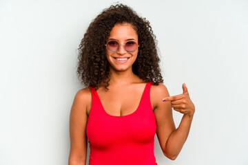 Young brazilian woman wearing a swimsuit isolated on blue background person pointing by hand to a shirt copy space, proud and confident