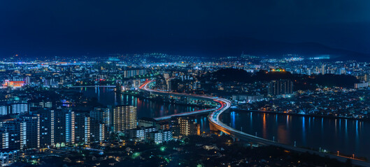 Bird's eye view of a night panorama cityscape of Fukuoka with the illuminated urban expressway...