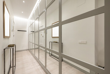 Narrow hallway in a home with an industrial-style appliance and a wall covered in gray-edged mirrors