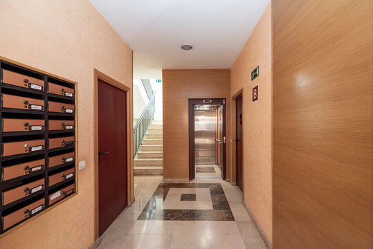 Portal of a residential apartment building with brass mailboxes, marble walls and floors and access to an elevator