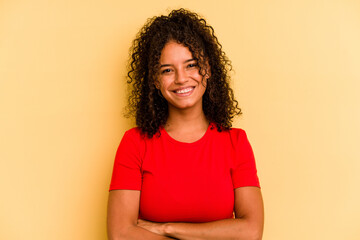 Young Brazilian woman isolated on yellow background who feels confident, crossing arms with...