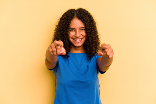 Young Brazilian woman isolated on yellow background cheerful smiles pointing to front.