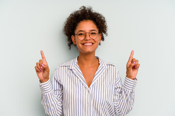 Young Brazilian woman isolated on blue background indicates with both fore fingers up showing a...