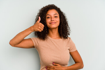 Young Brazilian woman isolated on blue background touches tummy, smiles gently, eating and...