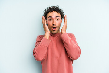 Young caucasian man isolated on blue background surprised and shocked.