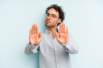 Young caucasian man isolated on blue background standing with outstretched hand showing stop sign,...