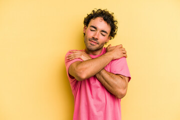 Young caucasian man isolated on yellow background hugs, smiling carefree and happy.