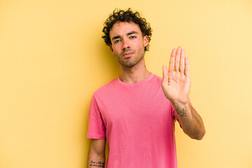 Young caucasian man isolated on yellow background standing with outstretched hand showing stop...