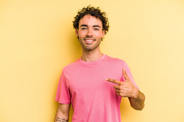 Obraz premium Young caucasian man isolated on yellow background person pointing by hand to a shirt copy space, proud and confident