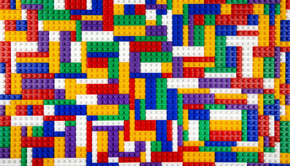 Abstract background texture of colored constructor blocks. Background of colorful plastic part of constructor. Pile of colored toy bricks.