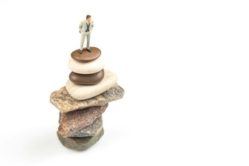Fototapeta na wymiar miniature people. the figure of a man stands on top of the stones. concept of achievements in life and success in business.