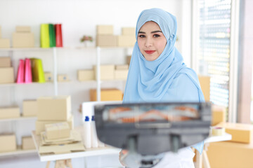 Active young beautiful asian housewife woman cleaning with vacuum cleaning floor after working SME with E-commerce Package box background. Cleaning girl in muslim black leggings vacuuming her room.