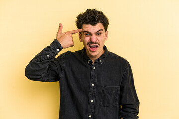 Fototapeta premium Young caucasian man isolated on yellow background showing a disappointment gesture with forefinger.