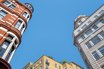 Generic London architecture in three styles and colours. Blue sky background with space for text.