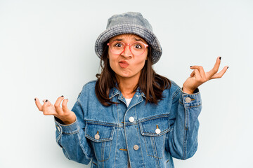 Young hispanic woman isolated on blue background shrugs shoulders and open eyes confused.