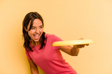 Young caucasian woman holding frisbee isolated on yellow background